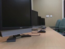 MS ZO Series of flat Dell computer screens and dell mice sit on a wooden table with blue chair / Doha, Qatar Stock Footage