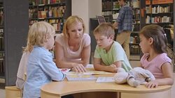 DS Woman and children reading a book in library Stock Footage