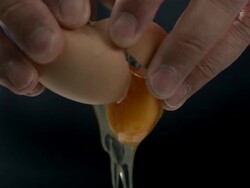 High speed Hands breaking egg, white and yolk spill out, against black Stock Footage