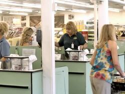 WS PAN middle-aged couple pushing full shopping cart out of cashier area to exit grocery store as young couple enter store and pushes empty shopping cart / Cabazon, California, USA Stock Footage