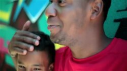 Father hugs and talks to son leaning on graffitied wall in Rio de Janeiro Stock Footage