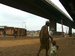WS PAN View of football players under bridge with old man and child passing / Lagos, Nigeria Stock Footage
