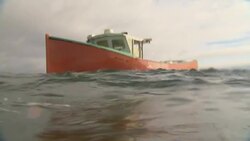 A small red boat lists on ocean waves. Stock Footage
