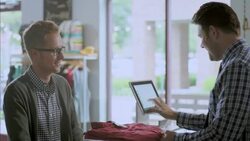 Customer brings shirt to cashier at checkout counter, swipes credit card, and signs name on iPad terminal square in trendy clothing shop Stock Footage