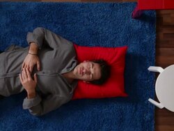 CU, ZO, man lying on a rug next to his home office desk, overhead view Stock Footage