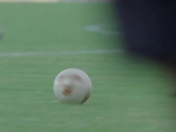 Slow motion pan of a pair of legs kicking a soccer ball Stock Footage