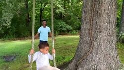 MS Smiling young boy being pushed on swing by father in backyard Stock Footage