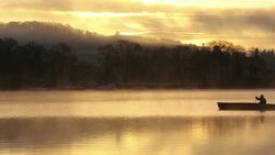 Mist at dawn over Lake Windermere, Lake District, UK, with a man in a Canadian Canoe. Stock Footage