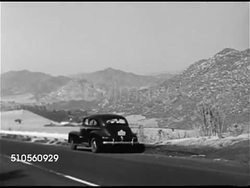 1948: CALIFORNIA MOUNTAINS: HA XWS Valley & mountains. Sedan pulling off road. Family in car, mother, father, two boys in matching striped shirts looking out windows. WS Valley w/ mountains BG. Boys at windows. Iconic, vacation, sightseeing. Instructional Video