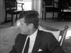 B/W 1962 close up PROFILE President John Kennedy sitting in chair talking to someone in White House Stock Footage