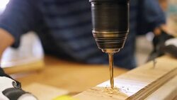 Close-up slow motion view of man using power drill to drill hole into 2 x 4 board Stock Footage