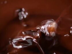 Ice cube dipping into a liquid chocolate  Stock Footage