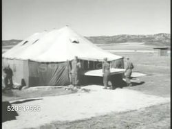 1951: KOREAN WAR: ARMISTICE TALK: VS Tents set up in negotiation camp south of Kaesong, U.S. Marines moving table into large tent. VS Soldiers raising round white barrage balloons. Instructional Video