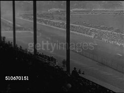1920s: AUTO RACING: HA WS (From covered seats) Track w/ cars racing by, WS Racecars taking curve, two cars in curve, HA WS One racecar skidding & going over fence backwards, HA WS Car skidding in dirt & into curve fencing.  Motorsports. Instructional Video