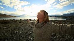 Young woman by the lakeshore arms outstretched Stock Footage