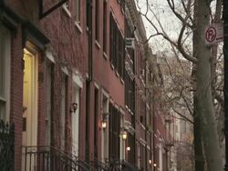 Slow camera move from the fire escape down to reveal brownstones from the sidewalk of a new york city street during the day Stock Footage