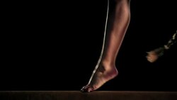 SLO MO Female gymnast doing back somersault on balance beam Stock Footage