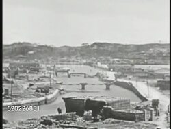 1945: OKINAWA, JAPAN: US SIXTH MARINE DIVISION TAKES NAHA: HA WS US Marines walking single file on street lined w/ rubble, destruction. HA WS Destroyed city bridges. Church w/ two walls standing. Tori gate in city center. Pacific Theater, WWII Instructional Video