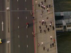 Aerial medim shot commuters and bicyclists passing over London Bridge with traffic / zoom out to wide shot of bridge with buildings on both sides of Thames in view / London, England Stock Footage