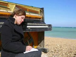 thoughtful young woman writing at the piano Stock Footage