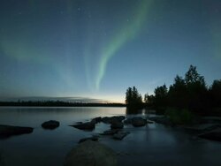 WS T/L View of aurora during early summer with rocks in foreground and reflection on calm water / Yellowknife, Northwest Territories, Canada  Stock Footage