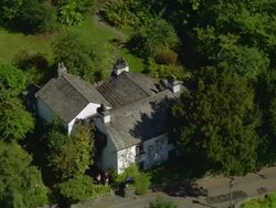 Aerial view of Dove Cottage and Wordsworth Museum / zoom out over village of Grasmere in the Lake District / Cumbria, England Stock Footage