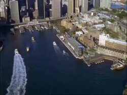 Aerial pan across Sydney Harbour Bridge, track high rise buildings, tilt down harbour, Australia Stock Footage
