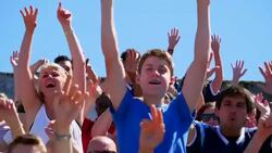 MS Crowd of football fans in stadium waving hands in air and standing up to cheer during game Stock Footage