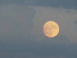 Moon at dusk with storm clouds in foreground, Cumulus towers and orange coloured moon. Stock Footage