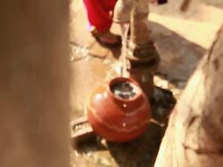 Young woman filled earthen pot with handpump in a village,  Stock Footage