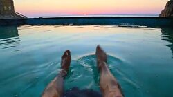 Guy from personal perspective swimming in a natural pool in the Mediterranean Sea Costa Brava recording his feet with the sunrise on the background in a stunning outdoor with great colors. Stock Footage