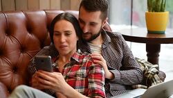 young couple sitting on sofa and using gadgets Stock Footage