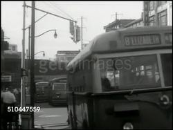 1949: ELIZABETHTOWN TRAFFIC: HA WS City, buildings, street, traffic. WS Buses driving by on street, traffic, pedestrians. MS Traffic officer waving, signaling. WS Vehicles in street traffic jam. WS Traffic jam, bridge & building BG. New Jersey Instructional Video