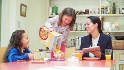 Playful girl pouring cereal overflowing bowl at breakfast table Stock Footage