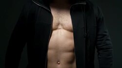 handsome young man with good muscles in a cape over a black background Stock Footage