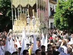 People watch the Costaleros bearing a large Trono in a procession with the hooded Nazarenos through the streets of Malaga, Andalucia, Spain, Europe Stock Footage