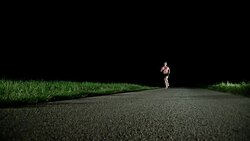 SLO MO PAN Female running on the road at night Stock Footage