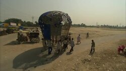 Festival participants transport pieces of a sculpture along a dirt road in India. Stock Footage