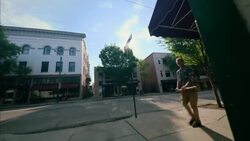 Young man carrying skateboard turns off downtown sidewalk to cut through brick alleyway Stock Footage