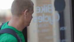 Small business owner walks up to store with bicycle and unlocks door Stock Footage