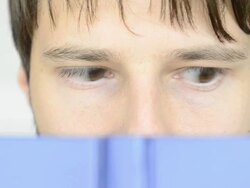 Close-up of Man's eyes reading blue book quickly Stock Footage