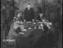 1941: JAPANESE FEARS: 'Rising Sun' flag of Imperial Japan flying on pole. Asian men in meeting at conference table, male putting on glasses, another smoking cigarette. COASTAL CONCERNS: WS Fishing boats in harbor. Group of fishermen pulling in nets. Instructional Video