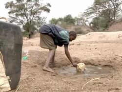 Boy spilling dirty water out of small water well Stock Footage