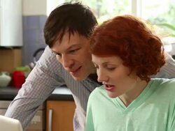 CU TU TD Shot of woman working on laptop in kitchen, man comes in and steals her toast while distracting her / London, United Kingdom Stock Footage