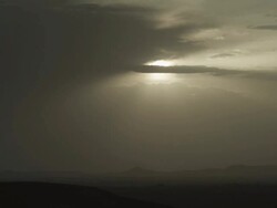 A large expanse of sky is divided by sunlight, with a darkening expanse of natural land below. Stock Footage