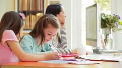 Mother working at computer next to daughters drawing in home office Stock Footage