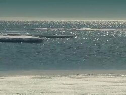 The sun shimmers on the Arctic Ocean, small ice flows drift in the water,  Stock Footage