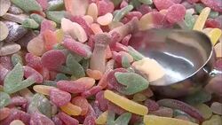 A scoop removes a portion of sour gummies. Stock Footage