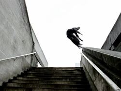Low angle medium shot freerunners running downstairs and jumping on railing Stock Footage