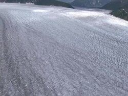 'Extreme Long Shot aerial push-in-A massive glacier winds past mountains in Alaska. / Alaska, USA' Stock Footage